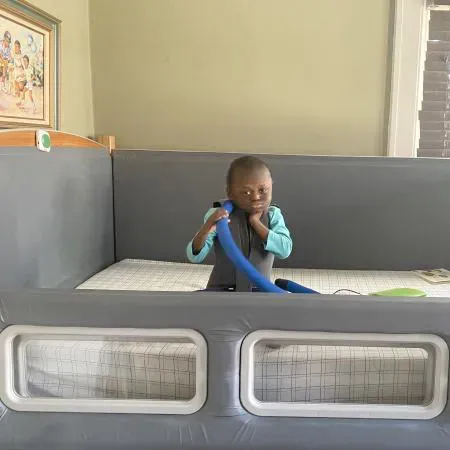 Young boy looking at camera while sitting in his new safety bed.